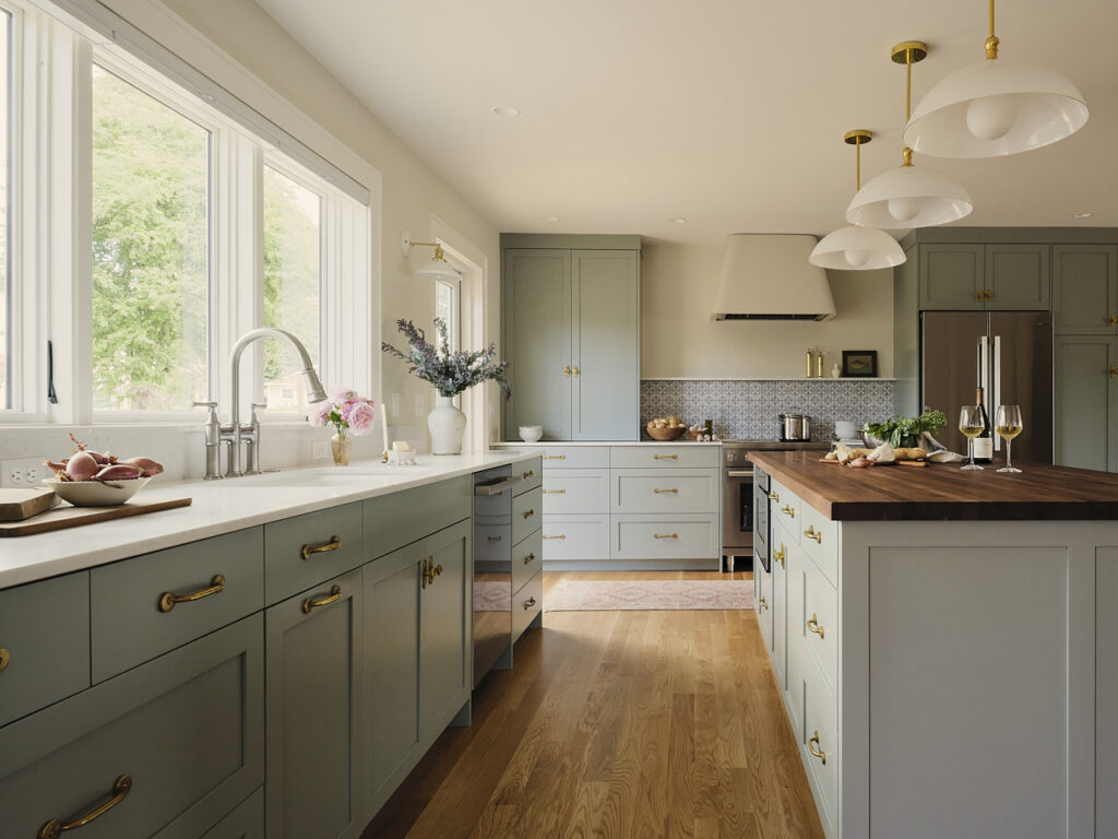 Bright kitchen with light blue cabinets, a wood island, and large windows letting in natural light.